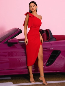Détail d'une robe rouge asymétrique avec nœud géant et fente latérale près d'une voiture