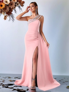 Détail d'une robe de soirée rose clair à une épaule avec bretelles perlées et fente latérale