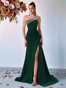 Détail d'une robe de soirée vert émeraude à une épaule avec perles et fente haute sexy