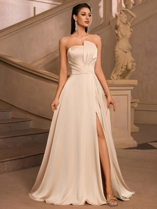 Close-up of elegant champagne satin dress with irregular pleated neckline and thigh-high slit