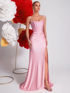 Pink satin mermaid evening gown with thin straps and side slit on a floral background