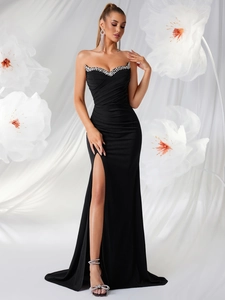 Détail d'une robe de soirée bustier noire avec bordure en strass et fente haute à plis élégants