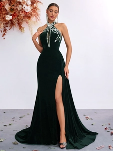 Detail of emerald green velvet evening dress with rhinestone halter neck and side slit