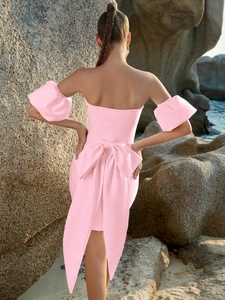 Détail du dos avec un grand nœud rose et des manches bouffantes élégantes sur cette robe chic
