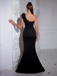 Rear view of sleek black one-shoulder evening gown with ruffled detail and high slit