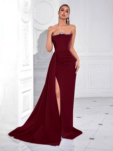 Close-up of strapless burgundy evening gown with rhinestone trim and side slit detail