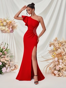 Close-up of red one-shoulder evening gown with ruffled details and rhinestone buckle