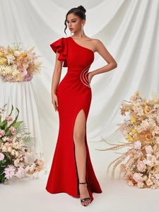 Detail of red one-shoulder evening gown featuring ruffled shoulder and side slit design