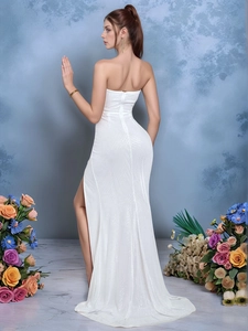 Detail of white sequin tube dress featuring elegant side slit and shimmering fabric texture