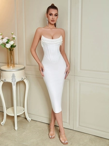 Detail of white corset dress featuring curved neckline and delicate tassel beadwork