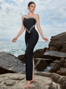 Detail of black bandage evening dress with silver rhinestones and cut-out on a rocky beach