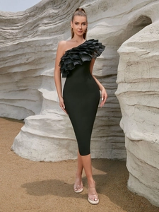 Dettagli in tulle nero arricciato su abito bandage monospalla su sfondo di rocce bianche