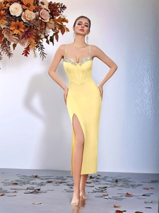 Detail view of bright yellow bandage dress featuring crystal-embellished neckline and side slit
