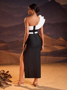 Detailed view of the one-shoulder white ruffle and slit hem on this black bandage gown