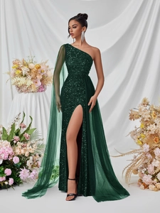 Detail of emerald green sequin gown with one-shoulder design and flowing mesh cape
