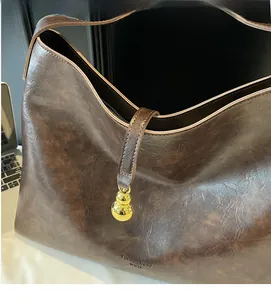 Detail view of dark coffee vintage tote bag with metal ball pendant and textured finish