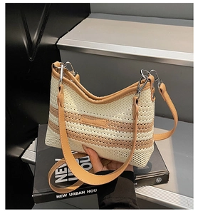 Close-up of woven bucket bag with brown leather trim and metallic strap hooks