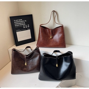Close-up of minimalist large tote bags in brown, dark coffee, and black with gold charms