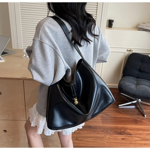 Detail of glossy black PU leather hobo bag featuring a decorative gold sphere pendant