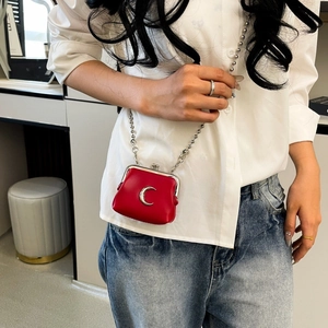Detailed view of mini red leather crossbody bag with silver moon charm and ball chain