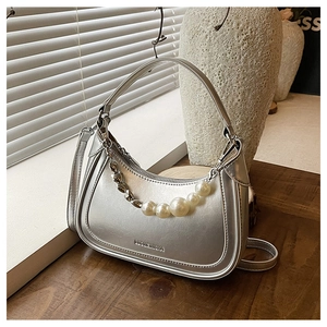 Detail of silver crescent bag featuring pearl heart chain and metallic finish texture