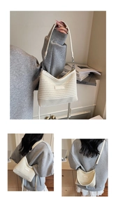Detailed macro view of cream-white woven texture and shoulder strap on bucket bag