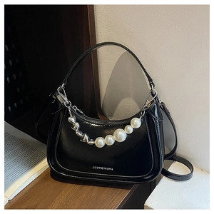 Detail of glossy black leather crescent bag featuring large pearls and silver heart beads