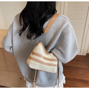 Detail of knitted bucket bag with contrasting stripes and adjustable leather shoulder strap