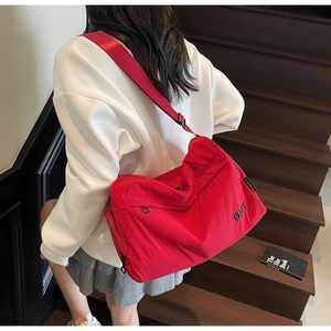 Détail du sac de voyage rouge avec imprimé BNT et sangle en nylon sur des escaliers