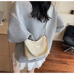 Close-up of cream knit bucket bag showing crochet texture and leather shoulder strap