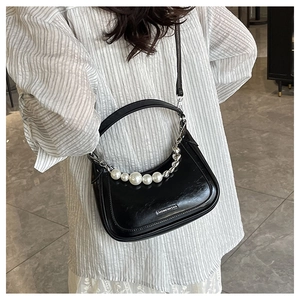 Detail of black crescent handbag featuring pearl chain and polished metallic logo