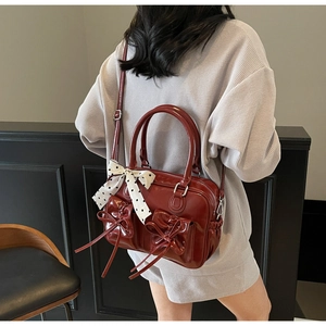 Dettaglio borsa Boston rosso scuro lucida con tasche a fiocco e nastro a pois