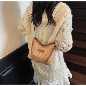 Detail of woven beige shoulder bag featuring brown leather trim and metallic brand plaque