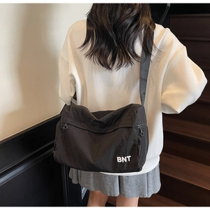 Détail du sac bandoulière en nylon noir avec logo BNT et large bandoulière réglable