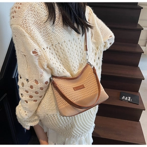 Detail of the woven straw bucket bag with brown leather trim worn by a model