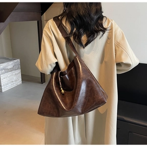 Detailed view of deep brown large tote bag in oily waxed leather worn by a model