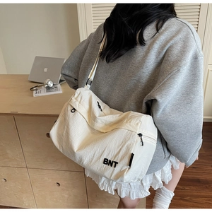 Détail du sac bandoulière en nylon blanc cassé avec logo BNT et plusieurs fermetures