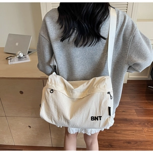 Sac de voyage minimaliste en nylon blanc avec broderie BNT porté par un mannequin chic