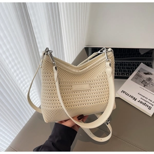 Detail of crochet knit texture and leather brand patch on stylish cream bucket bag