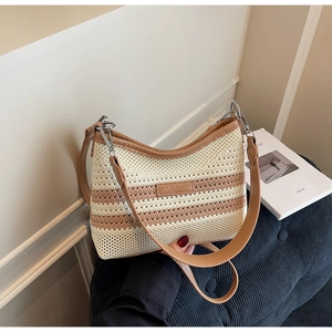Detail of woven straw bucket bag with contrast stripes and adjustable leather strap