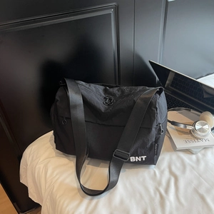 Détail du sac de voyage en nylon noir avec lettrage BNT blanc et large bandoulière