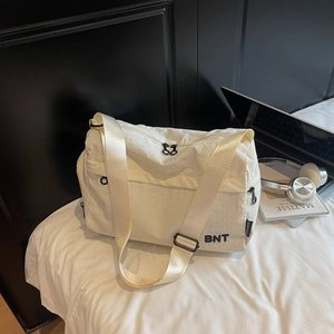 Détail du sac de voyage beige avec logo BNT et bandoulière réglable sur un bureau
