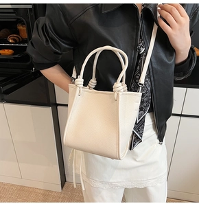 Détail d'un sac seau blanc crème avec poignées nouées et texture en cuir grainé