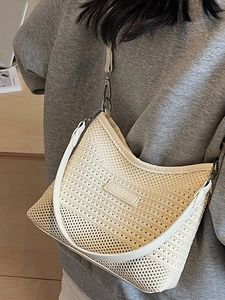 Minimalist beige woven bucket bag with leather strap and metal buckle worn by model