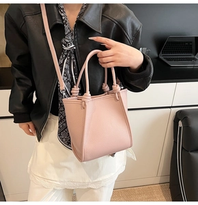 Détail du sac à main en cuir rose avec poignées nouées et bandoulière réglable amovible