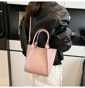 Détail du sac à main rose en cuir grainé avec poignée nouée et bandoulière amovible élégante