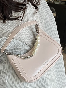 Elegant light pink underarm bag with pearl chain strap worn with white striped shirt