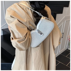 Detailed view of silver glossy baguette bag with metal buckle and shoulder strap