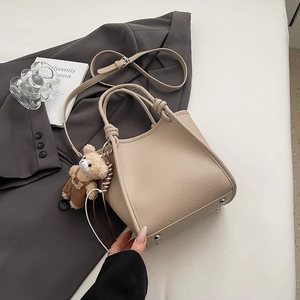 Détail du sac à main beige texture litchi avec breloque ours et bandoulière réglable