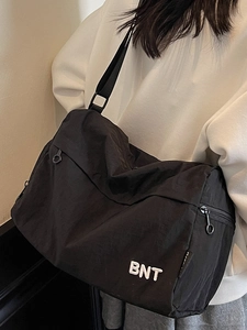 Sac bandoulière minimaliste en nylon noir avec broderie BNT porté par un mannequin